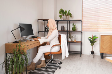 Muslim businesswoman working with computer at table in office