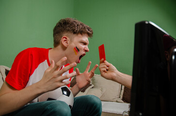 Red card on soccer match funny concept, fan yelling on tv , hand with red card coming through the...
