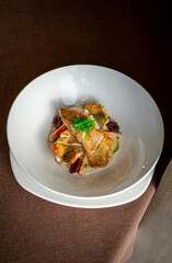 Seared fish fillets on sautéed vegetables with a creamy sauce, garnished with fresh herbs.
