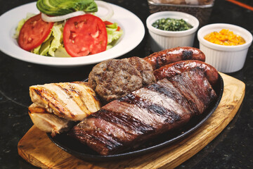 Juicy beef steak, a quarter grilled chicken, two artisan sausages and two mini burgers accompanied by fries and fresh salad.