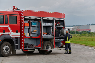 A firefighter meticulously prepares a modern firetruck for a mission to evacuate and respond to...