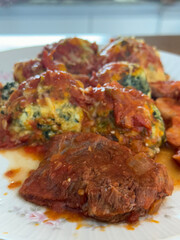Malfatis de ricota y espinaca con tuco de salsa de tomate, estofado y salchicha.