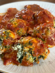 Malfatis de ricota y espinaca con tuco de salsa de tomate, estofado y salchicha.