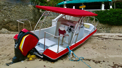 Boat washed ashore after a hurricane. A motorboat lies on its side on a sandy beach after a...