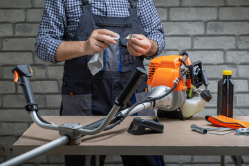 Man, repairman repairing, support petrol strimmer at workshop.