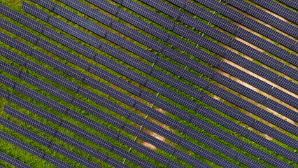 A field of solar panels is shown in a green field. The panels are arranged in a grid pattern, with...
