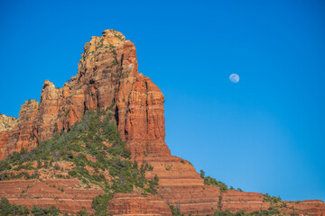 Moon rise over desert cliff monument at sunset with blue sky