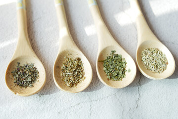 Four wooden spoons holding various spices on a table