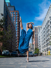 Beautiful Asian ballerina in blue dress posing in splits outdoors. Urban landscape. Vertical photo.  © Михаил Решетников