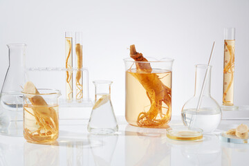 Various types of laboratory glassware with ginseng composition featured on white texture....