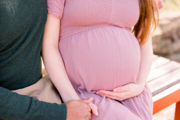 An interracial couple - an Indian man and Caucasian woman - sit together while the woman cradles her pregnant bump.