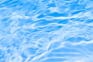 Fototapeta premium Blue water with ripples on the surface. Defocus blurred transparent blue colored clear calm water surface texture with splashes and bubbles. Water waves with shining pattern texture background.