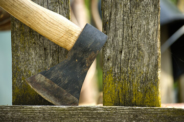 Detailed depiction of an axe embedded in an aged, weather wooden fence