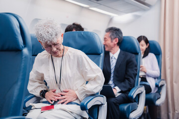 Fototapeta premium 飛行機の機内で体調不良に苦しむ高齢の女性
