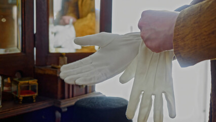 Close up of man in classic clothes putting on satin gloves. Stock footage. Retro background with...