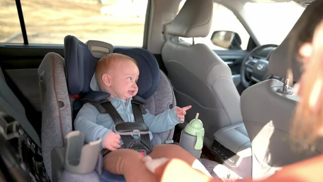 A mother prepares to unbuckle her baby from a car seat, ensuring the child's safety and comfort during the transition.