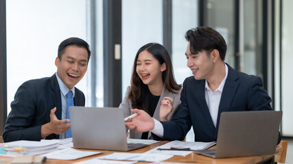 A group of young professionals happily collaborating on a project in a modern office environment.