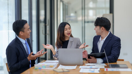 Business professionals in a meeting, discussing ideas and strategies with laptops and documents in...