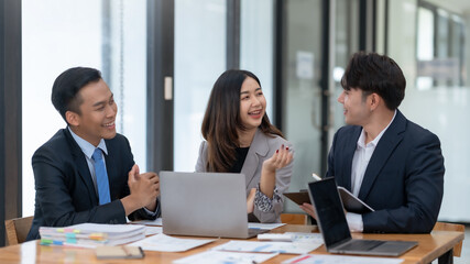 Colleagues collaborate in a modern office setting, discussing ideas and analyzing documents for a...