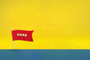 SALEの英語ブロックの赤い旗が風で揺れて立っている黄色い背景