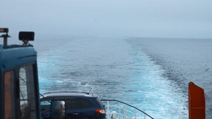 Ship with car sails into sea in cloudy weather. Clip. Sailing on ferry with car in sea. View of...