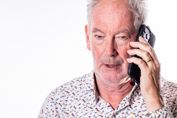 A close-up portrait of an elderly man with white hair and a beard, engaged in a phone conversation....