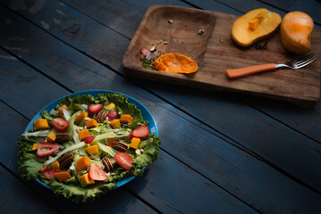 Comida. Ensalada recien preparada con una tabla de cortar con mango partido a la mitad, sobre mesa...