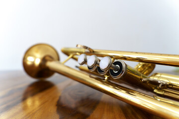 close-up of an old trumpet on a wooden table with a white wall in the background