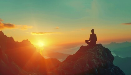 Silhouette of a person meditating on a mountain top at sunrise.