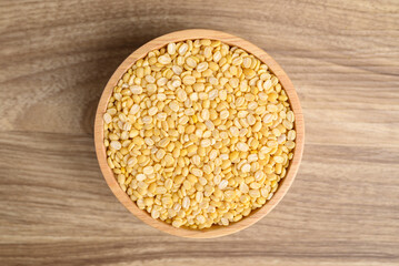Yellow peeled split mung bean in bowl on wooden background, Food ingredient, Table top view