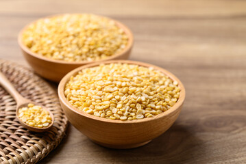 Yellow peeled split mung bean in bowl on wooden background, Food ingredient