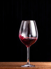 Glass of red wine on black background and on a wooden desk