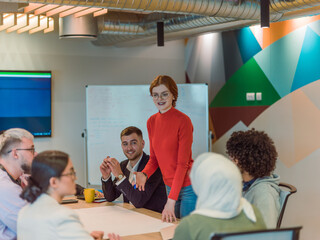 A diverse team of business experts in a modern glass office, attentively listening to a colleague's presentation, fostering collaboration and innovation