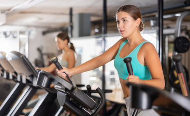 Young woman in sportswear training on treadmill in gym