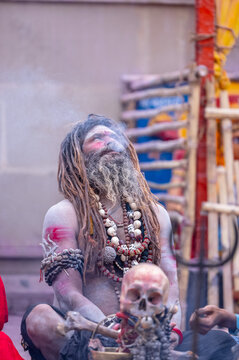 Portrait of an naga aghori sadhu holy man with pyre ash on his face and body performing aghor sadhna and smoking chilam at harishchandra ghat in varanasi.	

