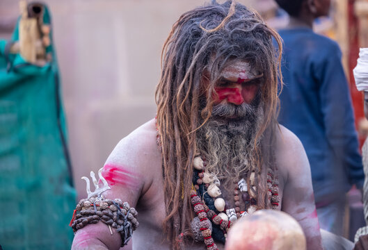 Portrait of an naga aghori sadhu holy man with pyre ash on his face and body performing aghor sadhna and smoking chilam at harishchandra ghat in varanasi.	

