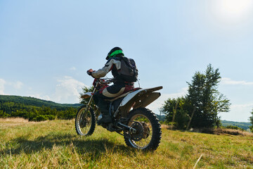 A motorcyclist equipped with professional gear, rides motocross on perilous meadows, training for...