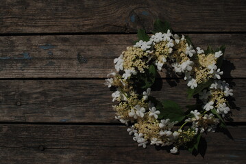 Wreath of white flowers on a dark wooden background.