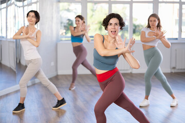 Woman in company of girls performs dance moves, attends modern dance studio and learns to dance hip-hop