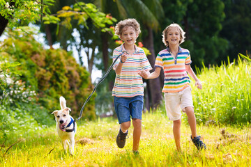 Kids play with dog. Children and puppy run in park