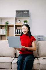 Young asian woman using smartphone and tablet while seated on couch at home