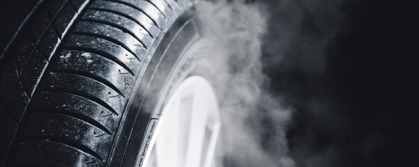 A Car tire with smoke surrounding it on a dark backdrop , horizontal banner with copy space , Car...