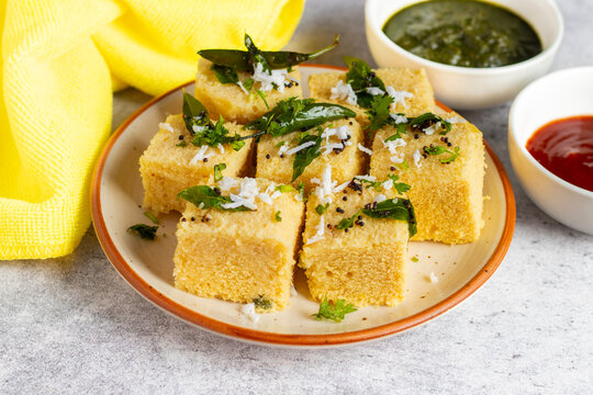 Famous Gujrati snack Dhokla made with gram flour and sugar syrup decorated with mint and tomato chutney. 