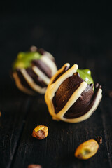 Two chocolate candies with green pistachio filling inside at black background