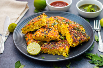 selective focus of Gujrati dish handvo slice tringle cut decorated with lemon, curry leaves, mint...