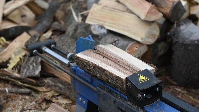 Hydraulic wood splitter splits wormwood. Preparation for the winter.