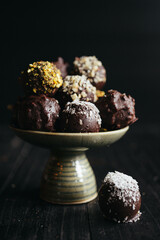 A still life of assorted chocolate truffles on the plate at dark background