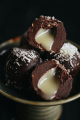A still life of chocolate truffles with liquid filling at dark background