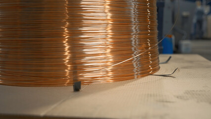 Close-up of wound copper wire in production. Creative. Thin line of wire on industrial coil....
