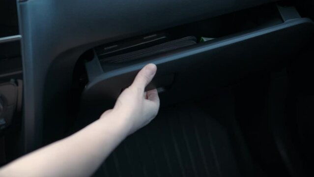 Use glove auto compartment. A woman hand use the compartment box in auto.